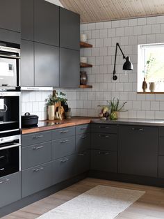 a kitchen with gray cabinets and white tile backsplash, wood flooring and open shelving