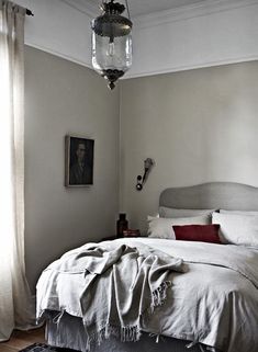 a bedroom with a bed, chandelier and pictures on the wall above it