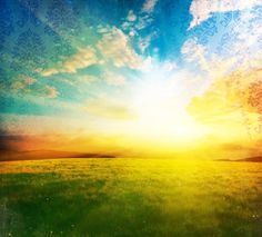 the sun is setting over a field with green grass and blue sky in the background