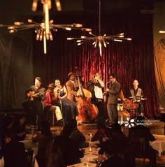 a group of people that are sitting in front of some lights and playing musical instruments