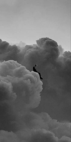 a man is flying through the clouds on top of a surfboard in black and white