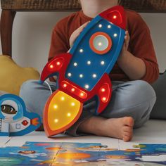 a young boy sitting on the floor with a toy rocket ship in front of him