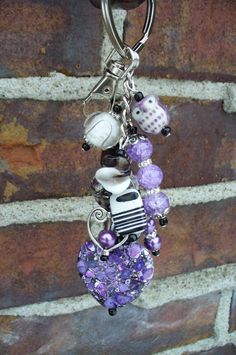 a keychain hanging from a brick wall with beads and charms attached to it