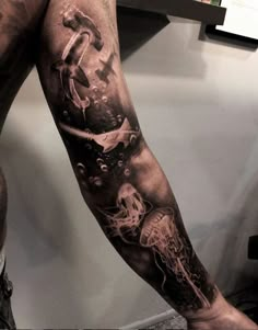 a man's arm with some tattoos on it and an anchor in the water