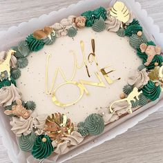 a cake decorated with gold and green icing in a box on a wooden table