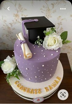 a purple graduation cake with white flowers on top