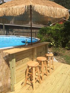 an outdoor bar with stools and umbrella next to a swimming pool in a backyard