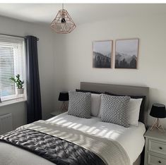 a bedroom with a bed, two lamps and pictures on the wall