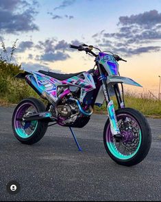 a motorcycle parked on the side of a road with blue and pink paint splatters