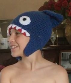 a young man wearing a knitted hat with a shark face on it