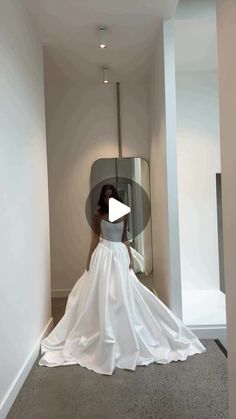 a woman in a white wedding dress is walking down the hallway with her back to the camera