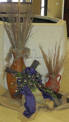 two vases with dried plants in them on the ground