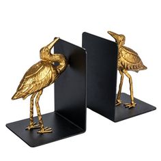 pair of gold - plated flamingo bookends on black stands, each holding an individual's head