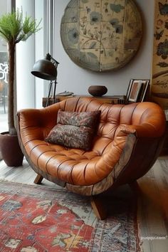 a brown leather chair sitting on top of a wooden floor next to a tree in a living room