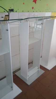 three white pedestals in the middle of a room with tile flooring and walls