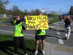 two girls holding up a sign that says tough here for power on the side of the road