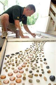 a man standing over a table filled with rocks