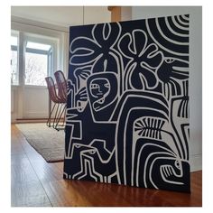 an abstract painting is displayed in the middle of a room with hardwood floors and windows