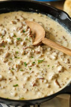 a skillet filled with meat and gravy on top of a wooden spoon