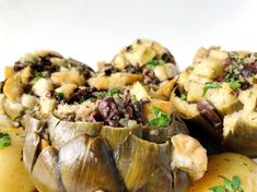 some artichokes are sitting on top of potatoes and garnished with herbs