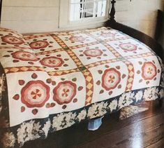 a bed with a quilt on top of it in a room next to a window