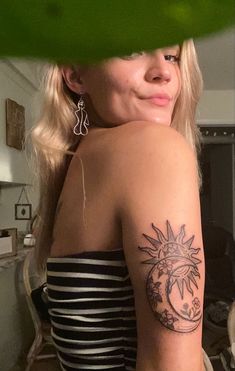 a woman with a sun and moon tattoo on her arm, looking at the camera