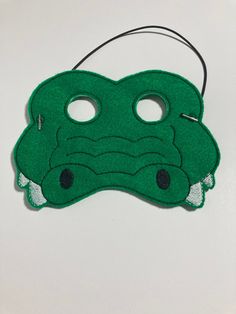 a green mask with two holes in the middle and an alligator's head on it