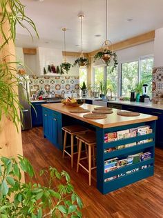 a kitchen with blue cabinets and wooden flooring next to an island in the middle