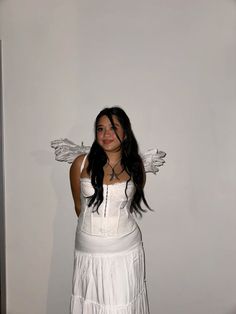 a woman in a white dress with angel wings on her head posing for the camera