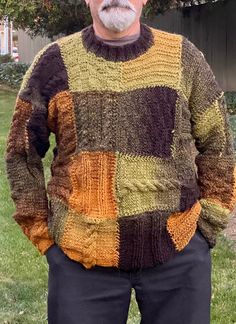 an older man wearing a multicolored sweater stands in front of a tree and grass area