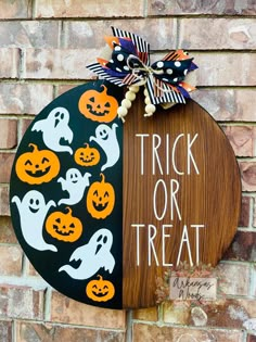 a trick or treat sign hanging on the side of a brick wall with halloween decorations