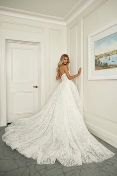 a woman in a wedding dress leaning against a wall with her back to the camera