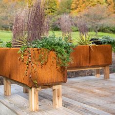 two wooden planters with plants growing out of them on top of a wooden deck