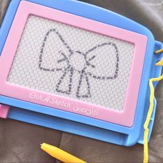 a blue and pink tablet with a bow drawn on it's screen next to some crayons