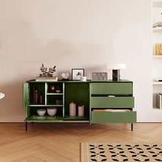 a green cabinet sitting on top of a hard wood floor next to a white wall