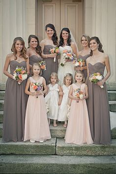 a group of women standing next to each other in front of a building holding bouquets