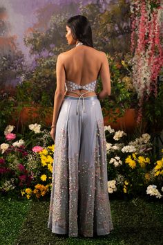 Element of fun and ethereal crafted in one ensemble. Sofia co-ord set consists of a halter neck top paired up with wide-legged pants accentuated with tassel drops. The ice-blue hue of the ensemble makes one look surreal and elegant while at the same time, the silhouette defines your bubbliness. Halter neck blouse embroidered with daisy motifs highlighted with sequins and flowers. Wide-legged pants with attached crisscross studded straps at the waistline crafted out of blingy sequined fabric high Indian Outfits Pants, Festive Party Palazzo Set With Tassels, Blue Palazzo Set For Spring Party, Elegant Sequined Palazzo Set For Summer, Chic Sets For Spring Reception, Chic Spring Reception Sets, Floor-length Spring Party Palazzo Set, Floor-length Palazzo Set For Spring Parties, Floor-length Palazzo Set For Summer Reception