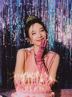 a woman sitting in front of a cake with candles on it