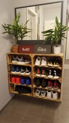 a wooden shoe rack filled with lots of shoes next to a large mirror on the wall