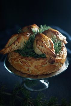 some food is sitting on top of a glass cake plate with pine cones and leaves