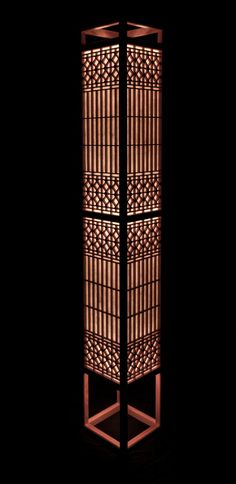 a tall wooden screen with lattice design in the center on a black background, lit by a light bulb