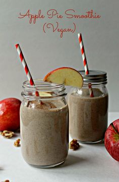 two mason jars filled with apple pie smoothie and an apple slice on the side