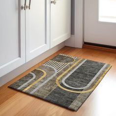 an area rug on the floor in front of white cabinets and cupboards with wooden floors