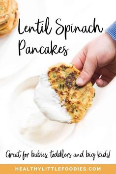 a hand holding a piece of food over a white plate with the words lentil spinach pancakes on it