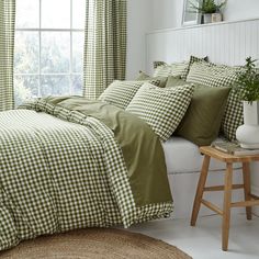 a green and white checkered comforter set on a bed in front of a window