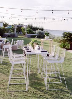 an outdoor dining area with white chairs and tables set up for dinner on the lawn