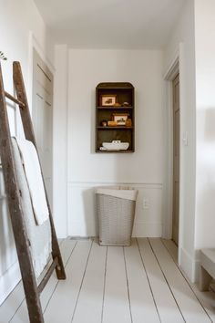 a bathroom with white walls and flooring next to a ladder