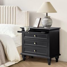 a black night stand with two drawers and a lamp on the nightstand next to it