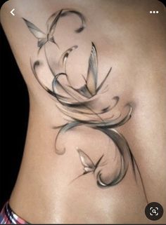 a woman's lower back tattoo with swirls and leaves on her stomach,