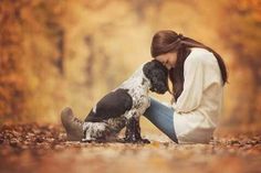 a woman sitting on the ground with her dog in front of her and looking at it